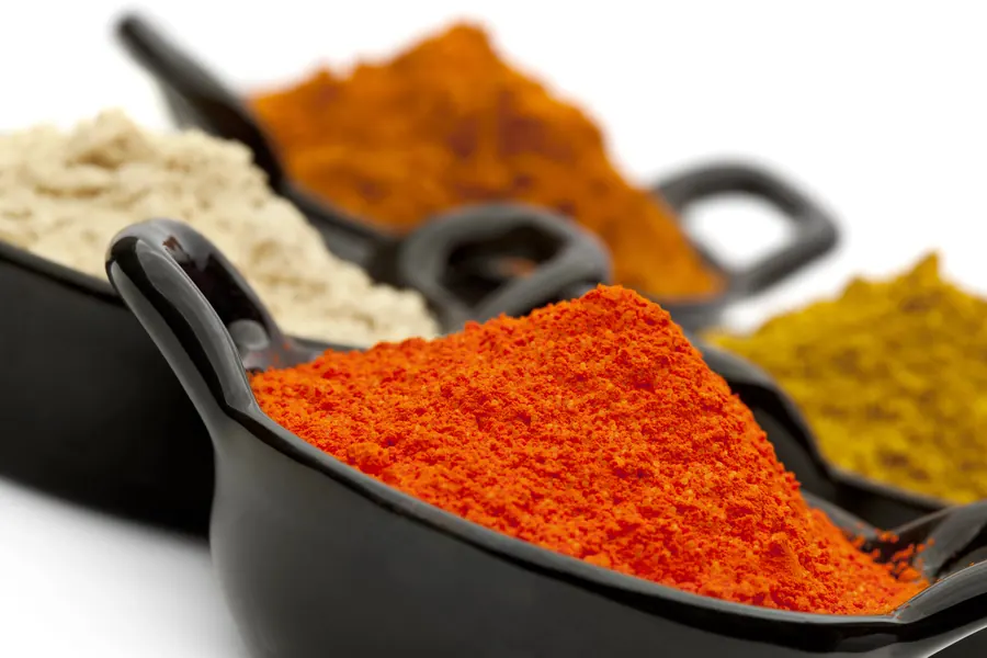 Condimentos en polvo de colores en recipientes negros