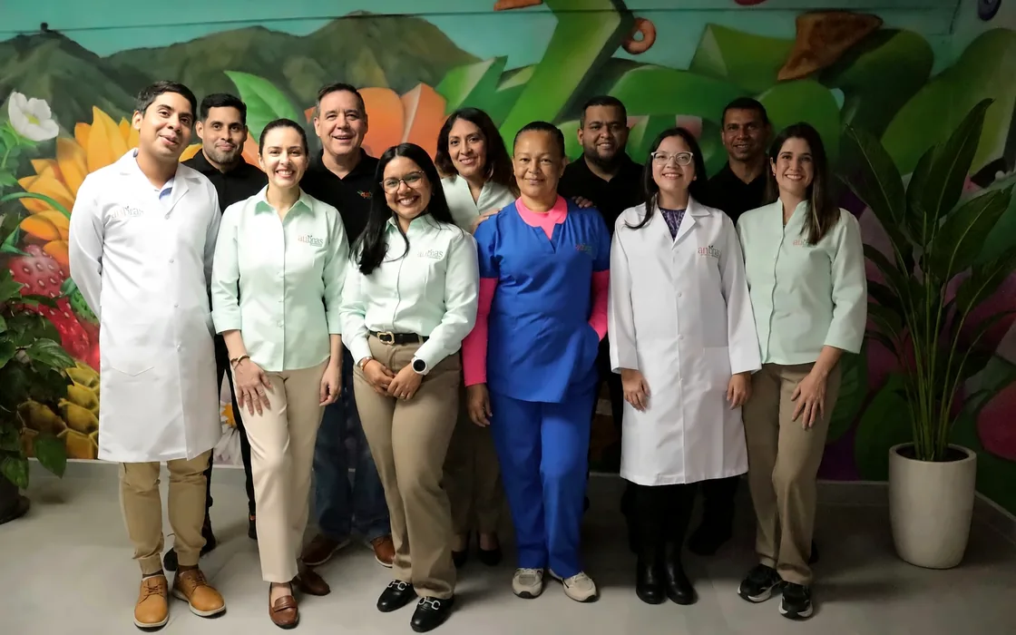 Equipo de Anbras® con su uniforme y batas de laboratorio frente a un mural de frutas