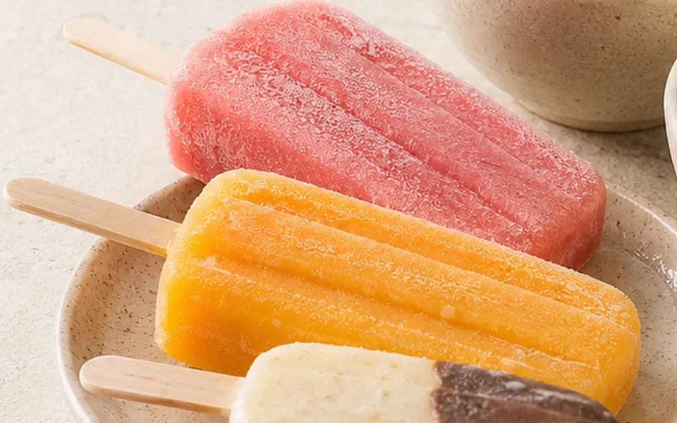Paletas de helado de fresa, mango y vainilla con chocolate en un plato