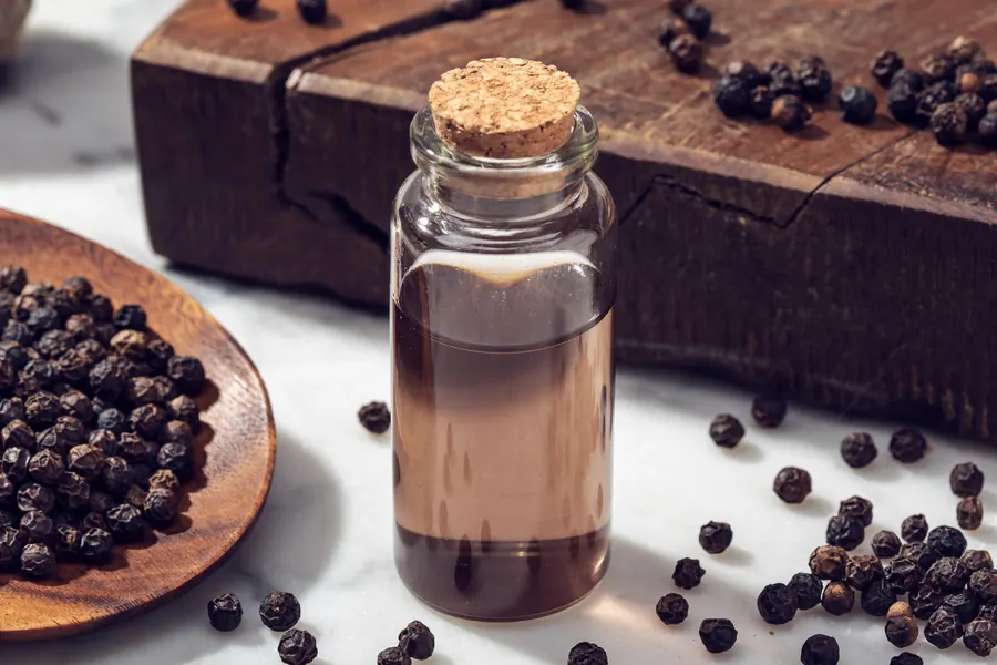 Frasco de oleorresina de pimienta con granos de pimienta negra